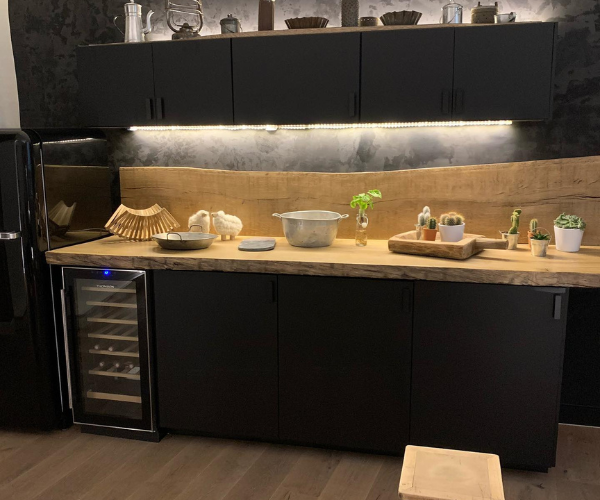 Cuisine de standing rénovée avec meubles noirs et plan de travail en bois à Lyon