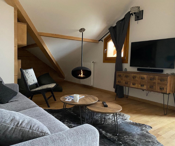 Salon rénové avec cheminée suspendue dans un appartement de montagne à Vaujany